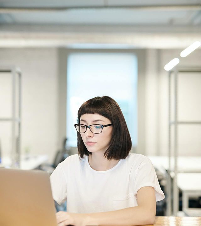 Mujer joven trabajando en una laptop en una oficina moderna